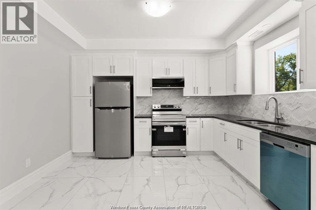 A kitchen with white cabinets and a marble floor.