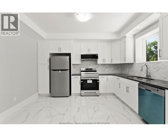 A kitchen with white cabinets and a marble floor.