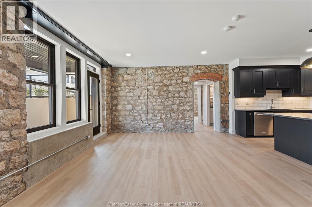 A spacious room with wooden flooring and a stone wall.