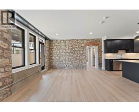A spacious room with wooden flooring and a stone wall.