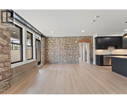 A spacious room with wooden flooring and a stone wall.