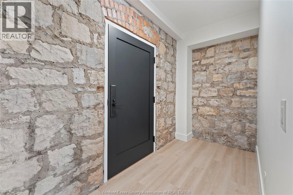 A black door is in a room with a stone wall.