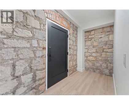 A black door is in a room with a stone wall.