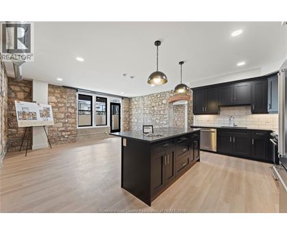 A kitchen with black cabinets and a stone wall.