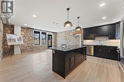 A kitchen with black cabinets and a stone wall.