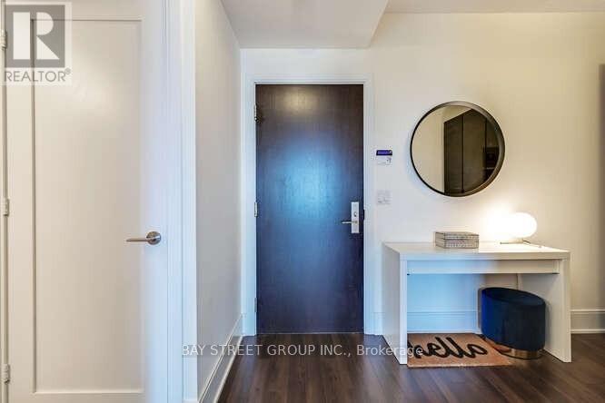 A hallway with a white door, a mirror, and a desk with a lamp.