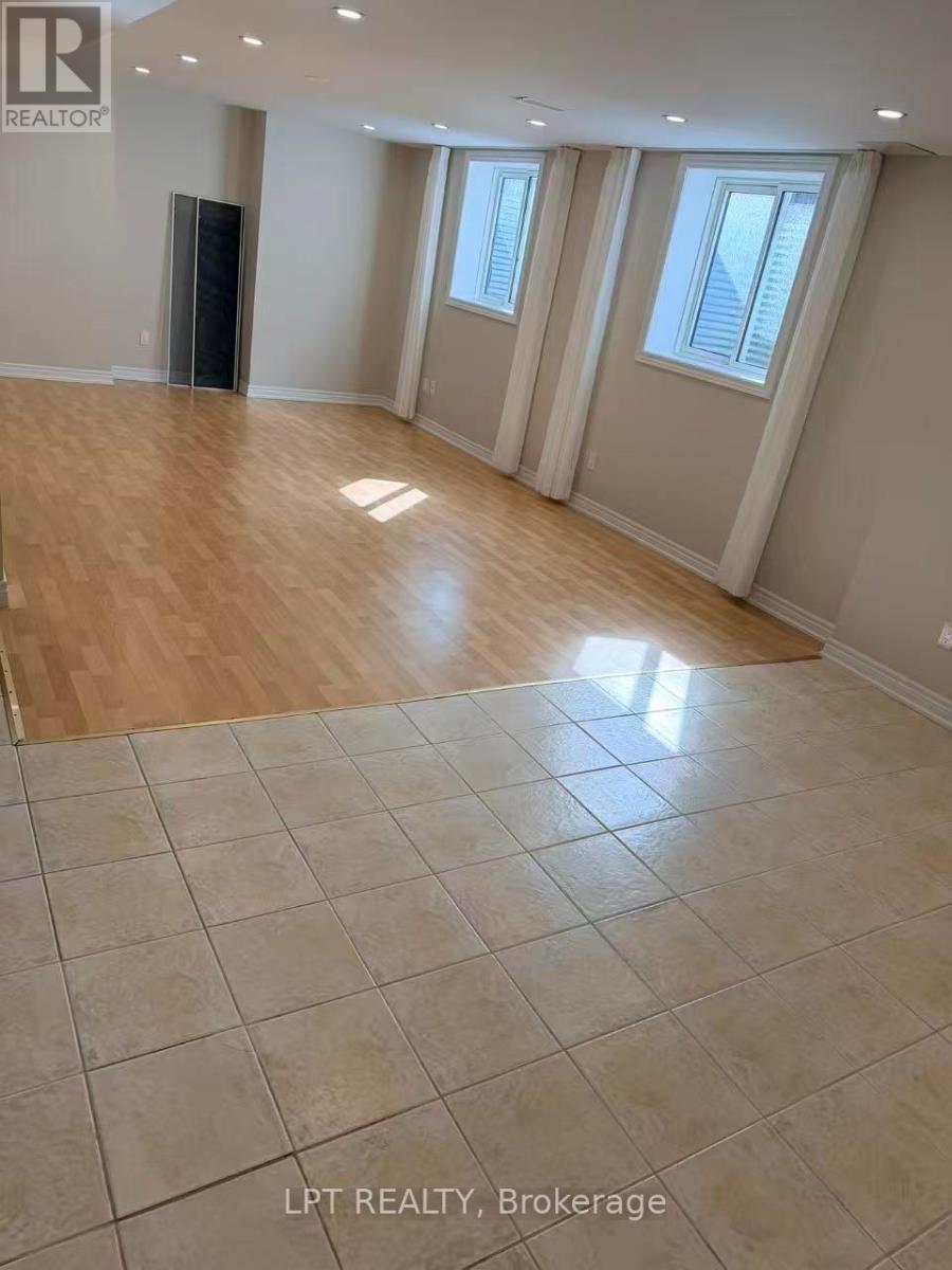 A spacious room with wooden flooring and tiled flooring in the foreground.