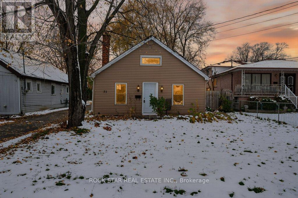 A house with a snowy front yard and a tree in front of it.