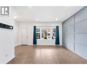 A spacious room with wooden flooring and a large window with curtains.