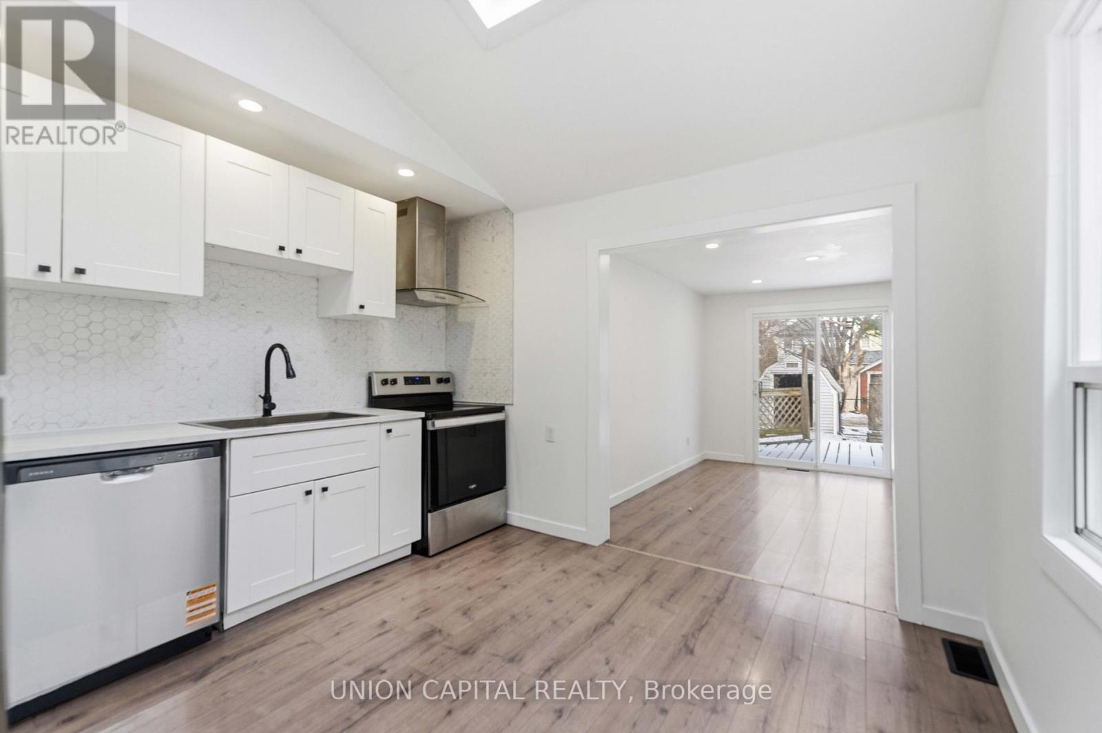 A kitchen with white cabinets and a black fridge.