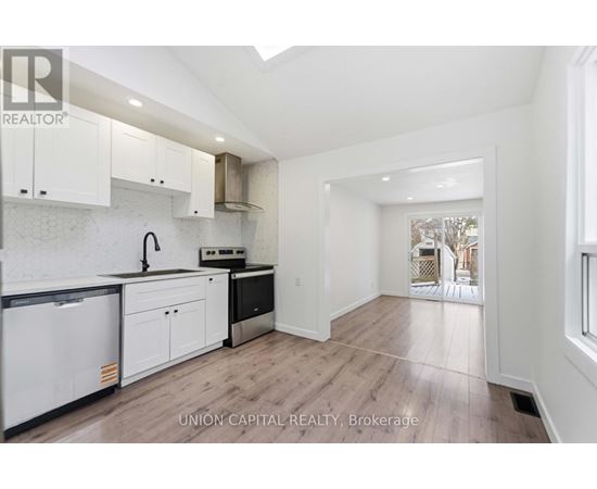 A kitchen with white cabinets and a black fridge.
