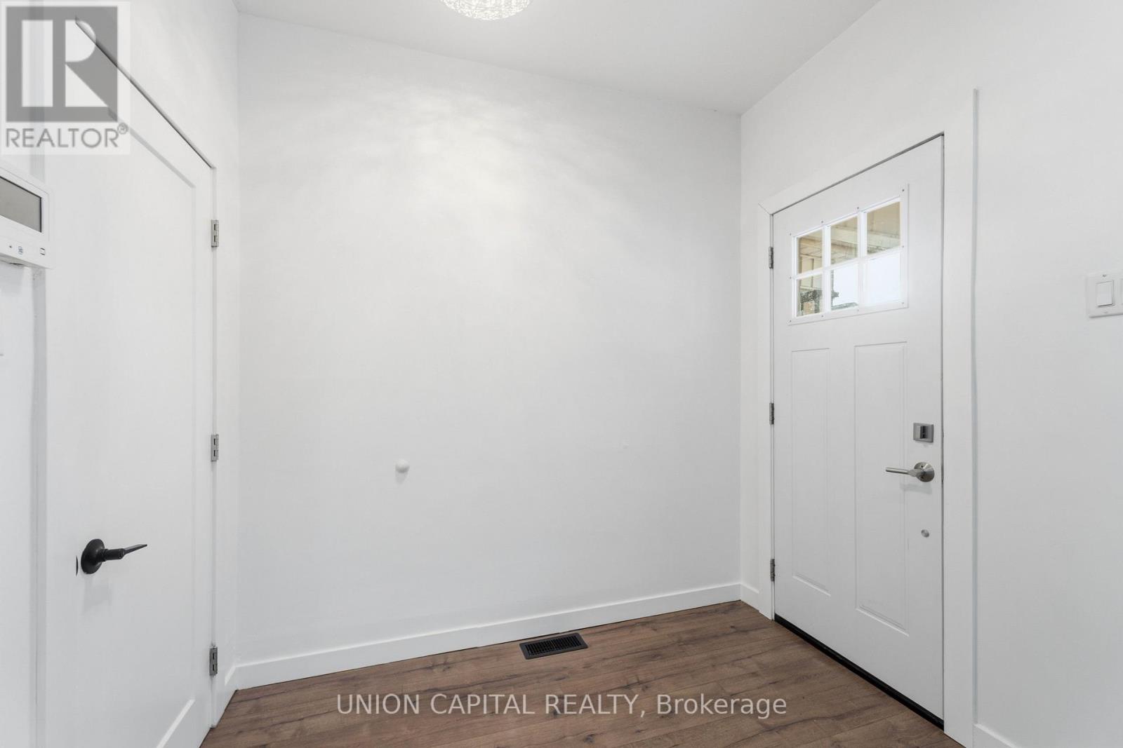 A white door is on the left and a white door with a window is on the right in a white room.