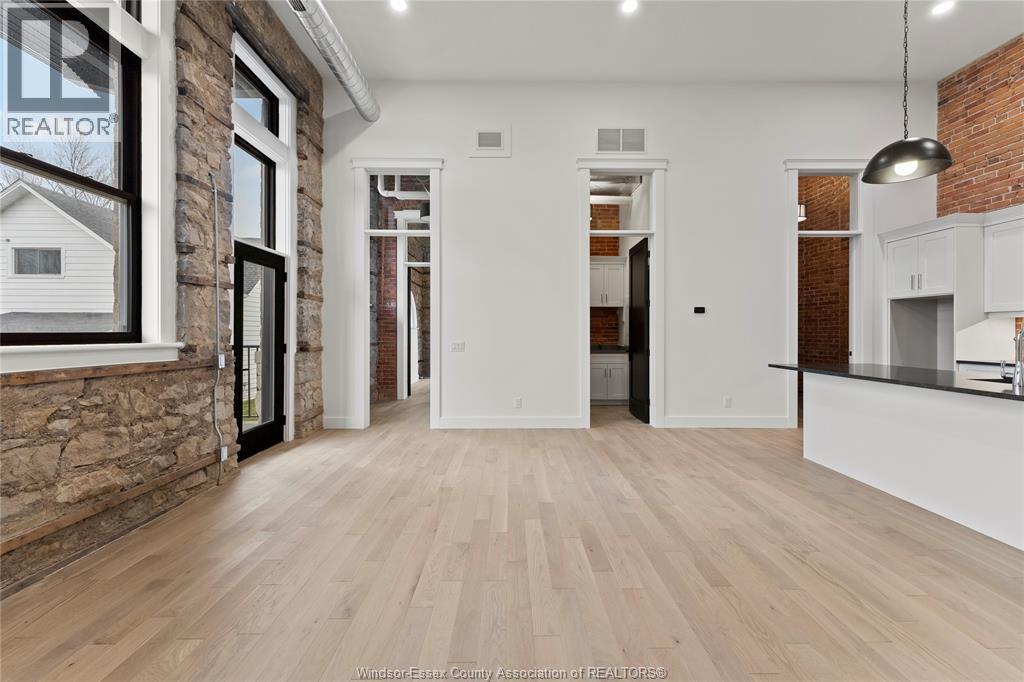 A spacious room with wooden flooring and a brick wall.