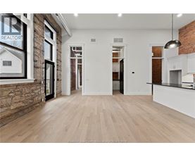 A spacious room with wooden flooring and a brick wall.