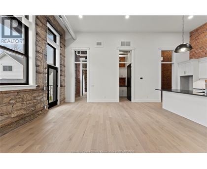 A spacious room with wooden flooring and a brick wall.