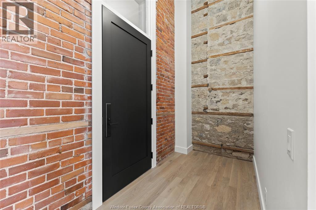 A black door is in a room with a brick wall.