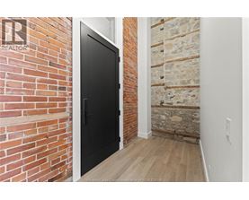 A black door is in a room with a brick wall.