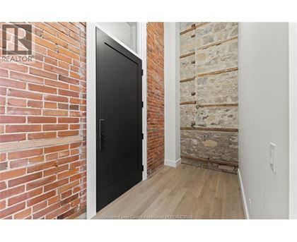 A black door is in a room with a brick wall.