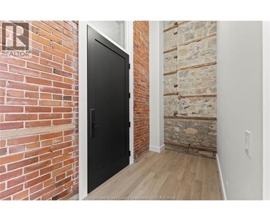 A black door is in a room with a brick wall.