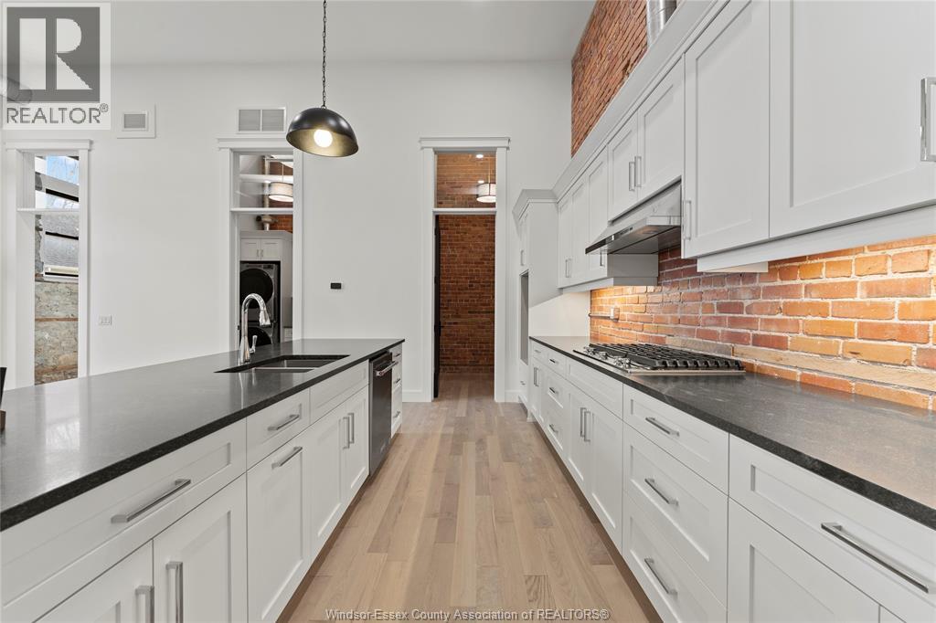 A kitchen with white cabinets and a brick wall.