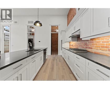 A kitchen with white cabinets and a brick wall.