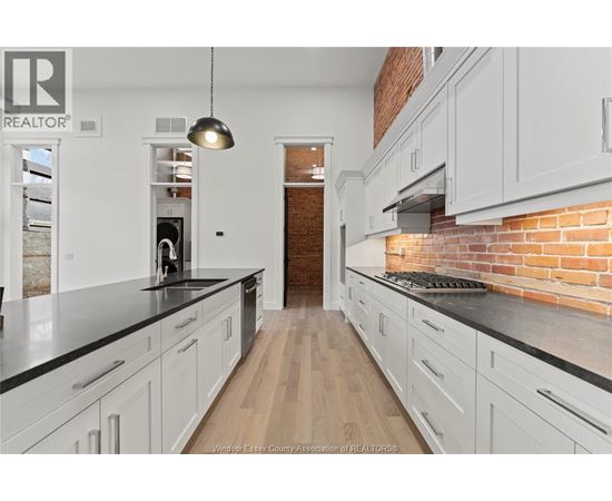 A kitchen with white cabinets and a brick wall.
