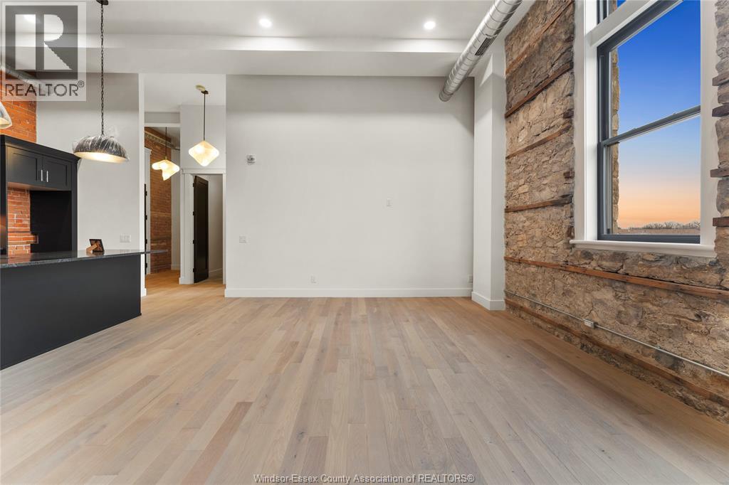 A spacious room with wooden flooring and a brick wall.