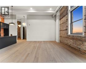 A spacious room with wooden flooring and a brick wall.