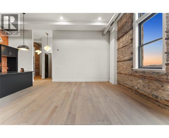 A spacious room with wooden flooring and a brick wall.