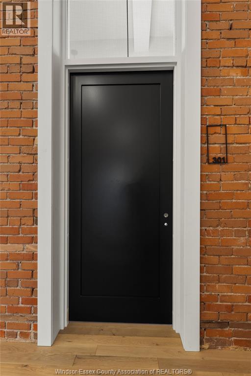 A black door is set in a brick wall.