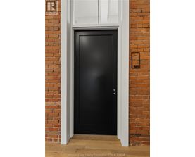 A black door is set in a brick wall.