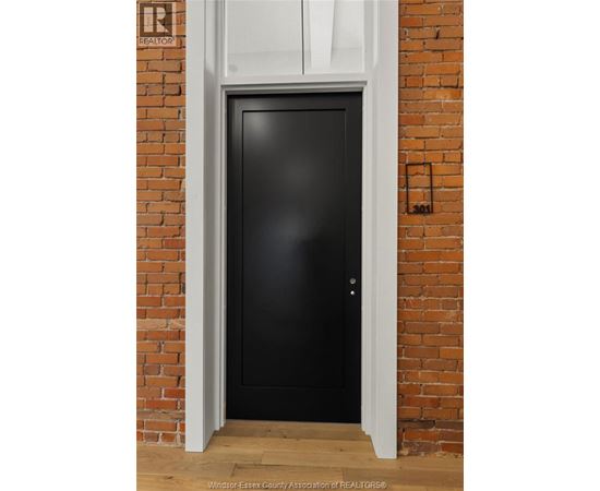 A black door is set in a brick wall.