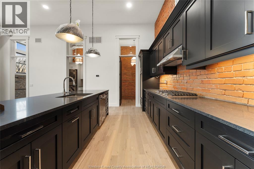 A kitchen with black cabinets and a brick wall.