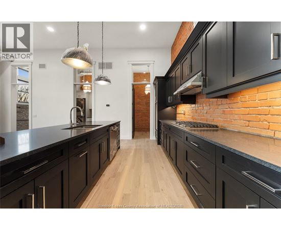 A kitchen with black cabinets and a brick wall.