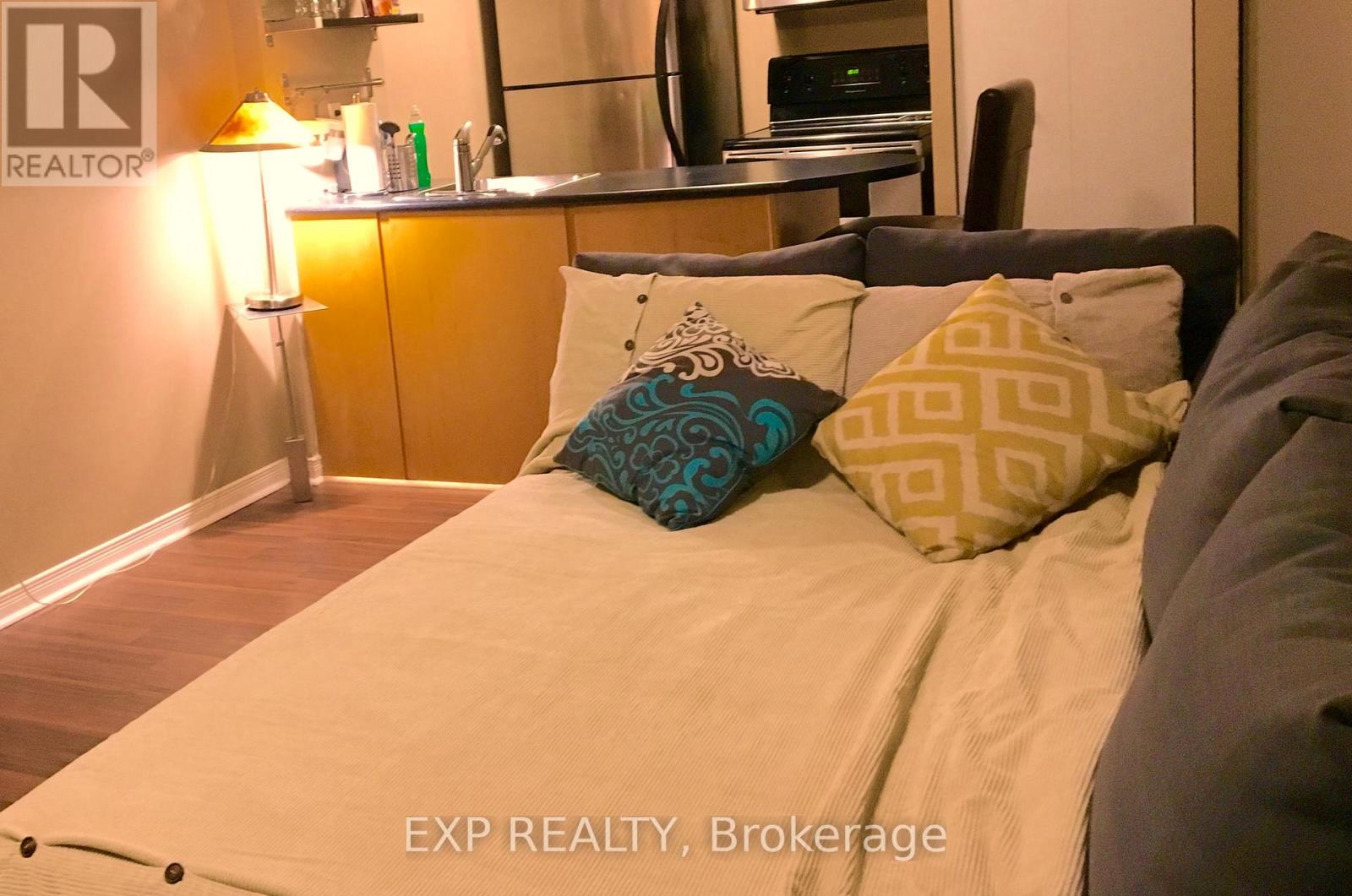 A bedroom with a bed, a couch, and a lamp.