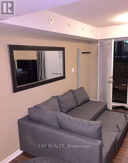 A grey couch sits in a living room with a large mirror above it.