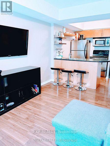 A kitchen with a bar stool and a television.