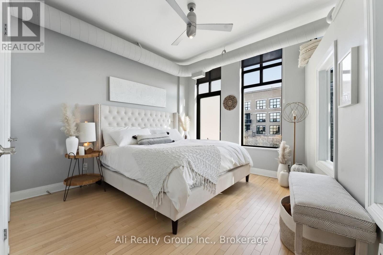 A well-lit bedroom with a large bed and a window showing a city view.
