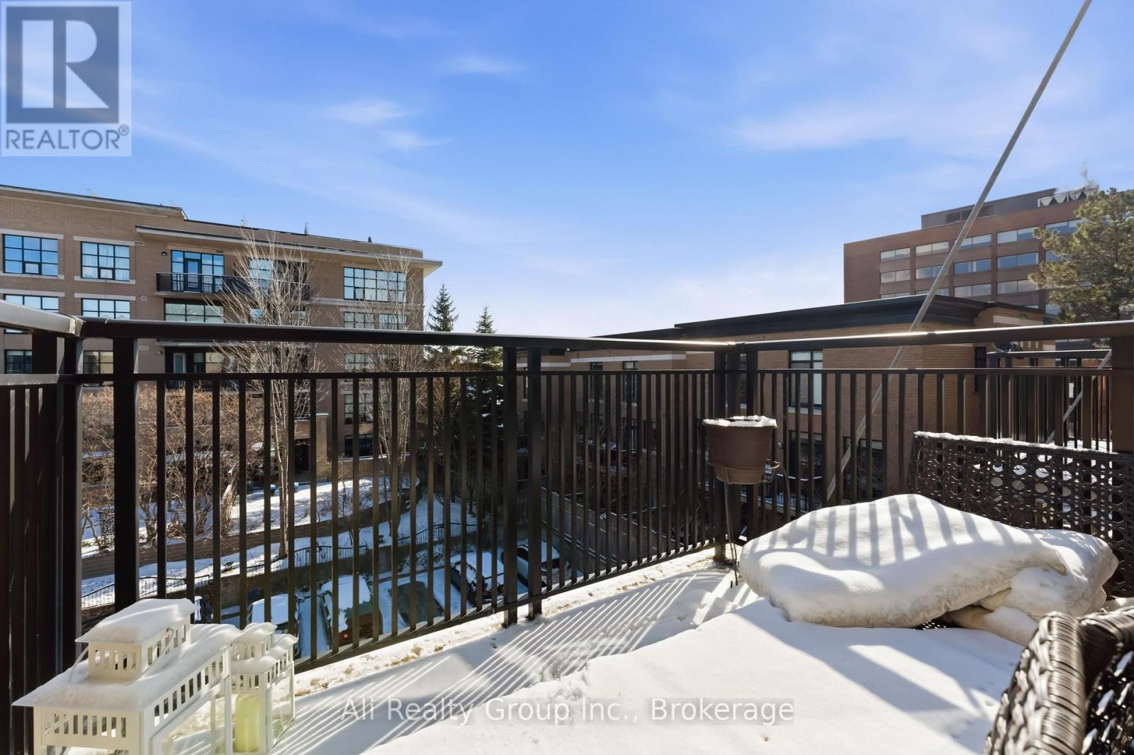 A pool surrounded by a black fence with a white couch and pillow on the ground.