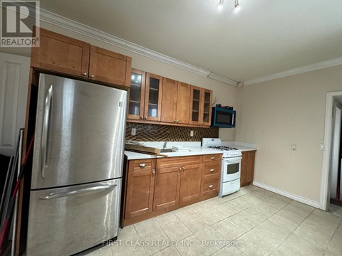 A kitchen with a refrigerator, microwave, and oven.