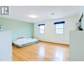 A bedroom with a bed, a window with blue blinds, and a wooden floor.