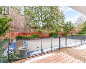 A backyard with a fenced pool and a hot tub.
