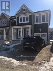 A black car is parked in front of a grey house.