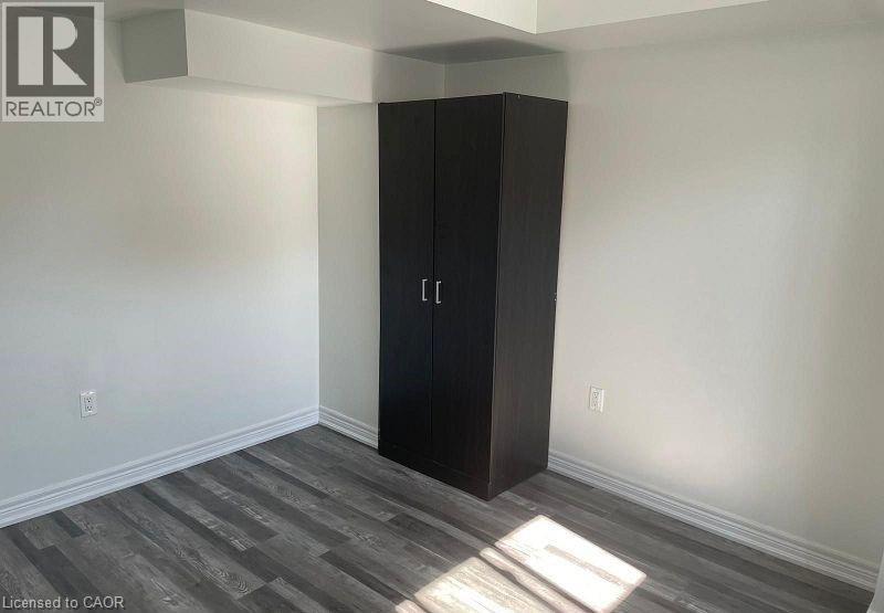 A room with a black wardrobe and wooden flooring.