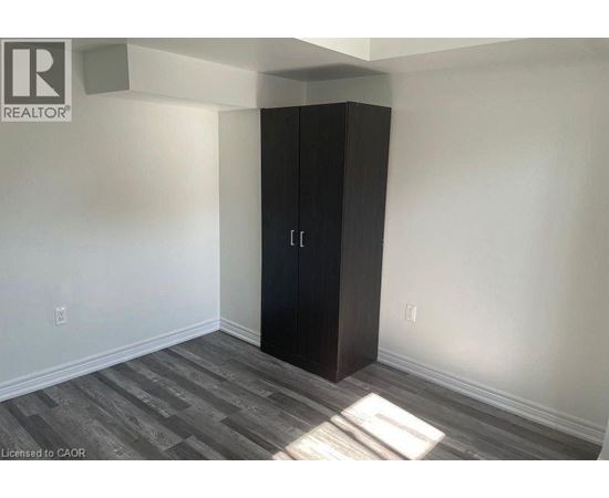 A room with a black wardrobe and wooden flooring.