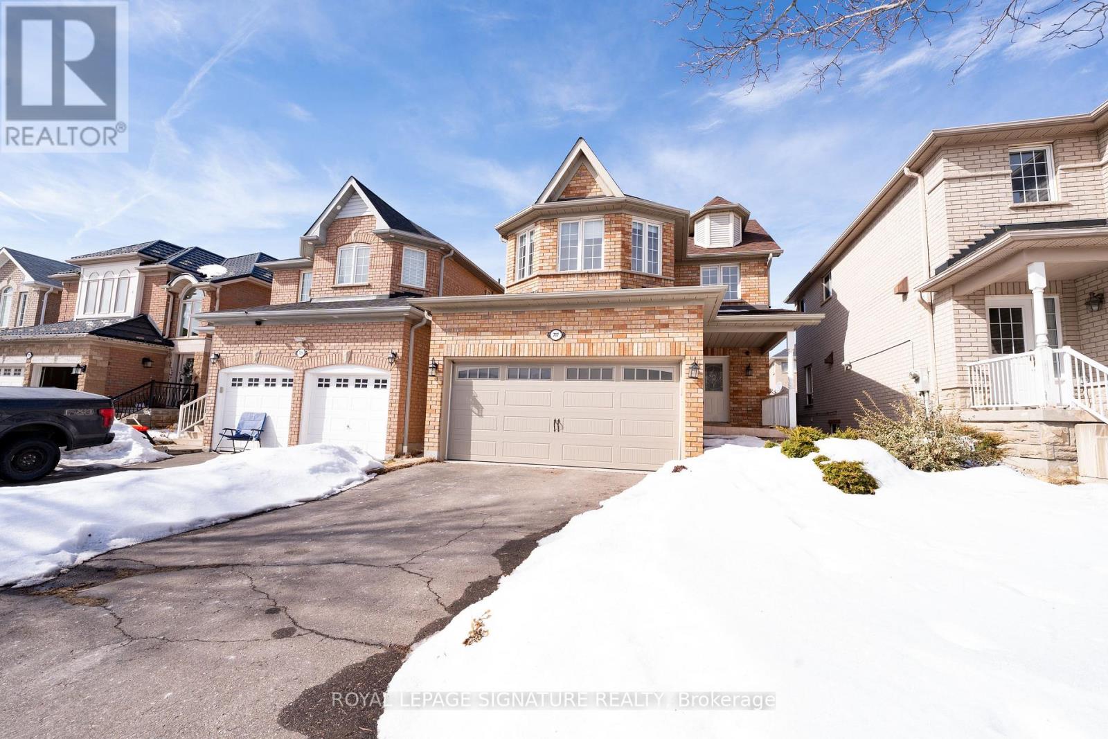 A large, luxurious house with a driveway and garage is for sale.