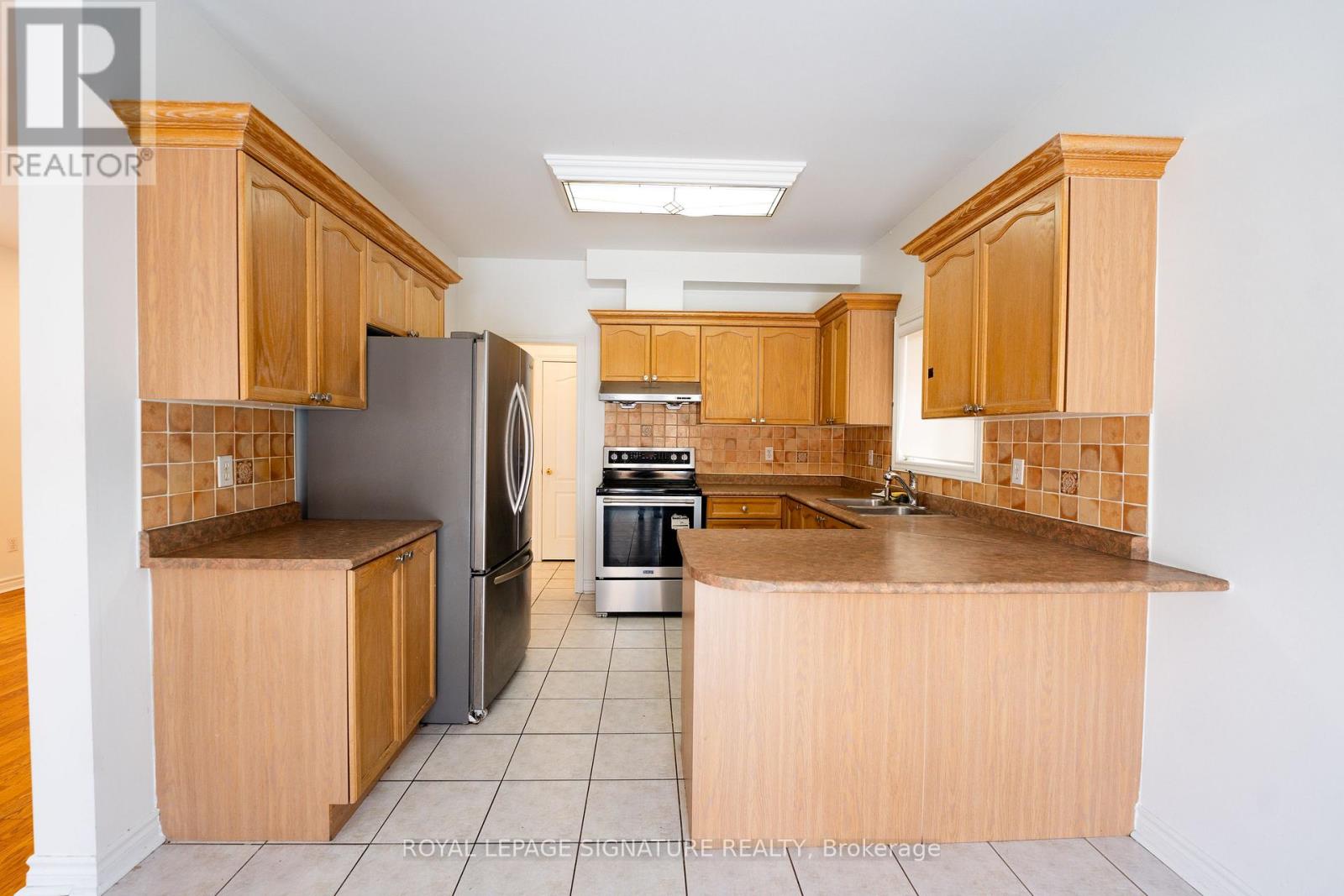 A kitchen with wooden cabinets and a tiled floor.