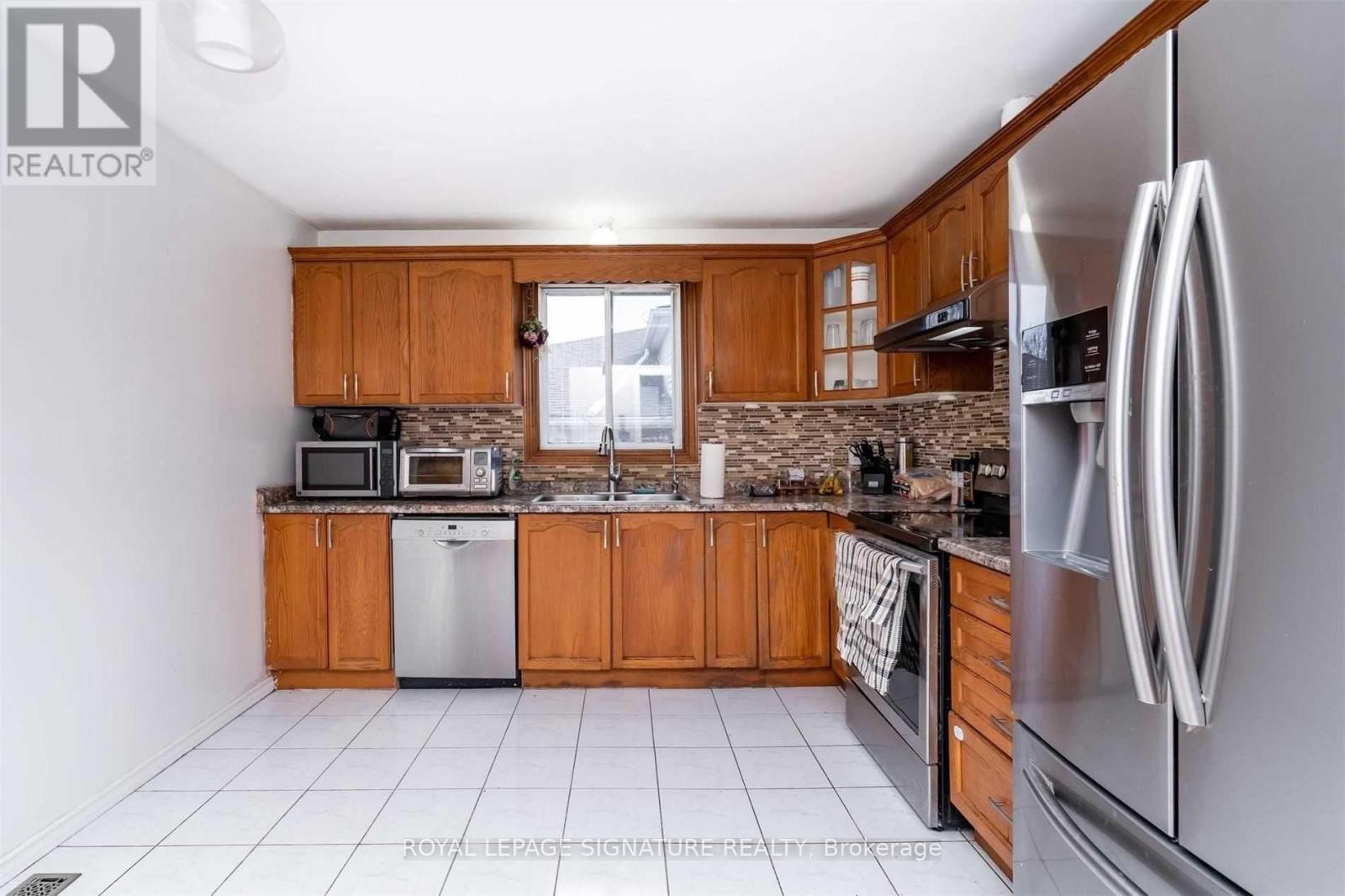 A kitchen with wooden cabinets and a stainless steel refrigerator.