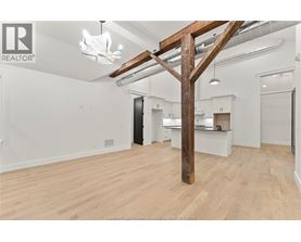 A spacious room with wooden floors and a large wooden beam structure.