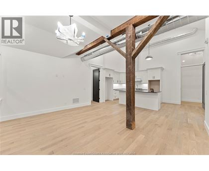 A spacious room with wooden floors and a large wooden beam structure.